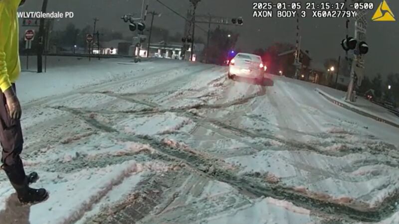 A car stuck in snow on some train tracks was nearly hit before an officer and bystanders...
