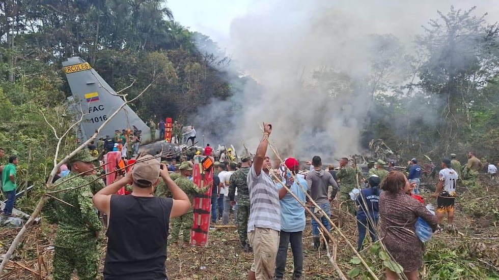 People stand around a military cargo plane that crashed after taking off from Puerto...