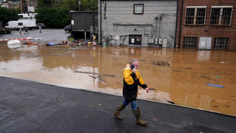 FILE - A man walks near a flooded area near the Swannanoa river, effects from Hurricane Helene...