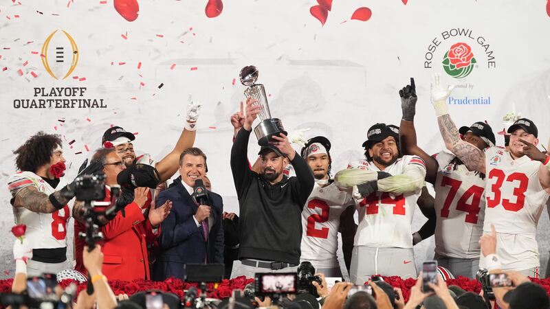 Ohio State head coach Ryan Day celebrates with the trophy alongside his team after winning the...