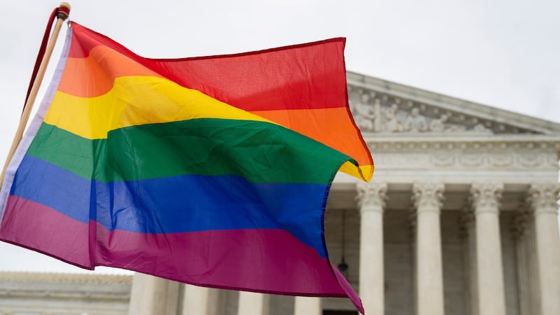 FILE - Supporters of the LGBT wave their flag in front of the U.S. Supreme Cour, Oct. 8, 2019,...